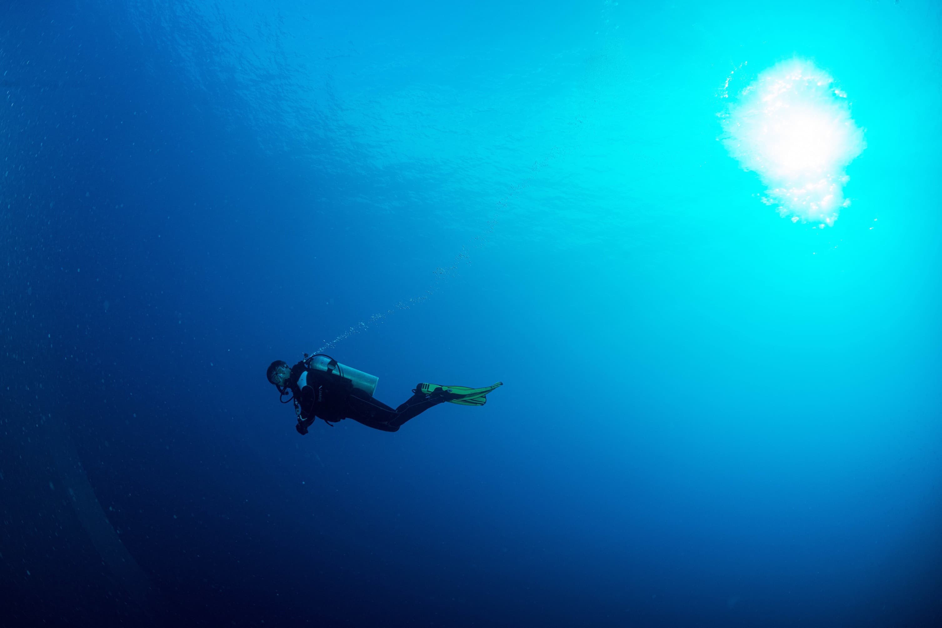 A diver in deep blue water in Apo Reef Natural Park by Jeru Cajapin